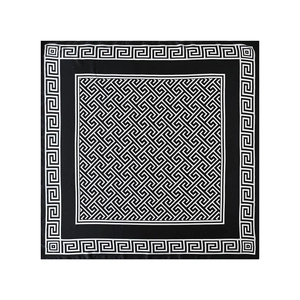 Détail à plat d'un foulard carré en satin noir et blanc avec bordure de méandres grecs