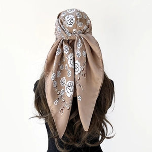 Dettaglio di elegante foulard in raso con stampa floreale moka e motivi a catena dorata