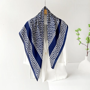 Carré de soie satiné bleu marine et blanc avec motif grec présenté sur une veste chic