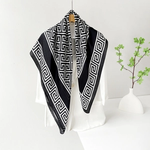 Élégant foulard en soie noir et blanc à motif géométrique sur un blazer blanc moderne