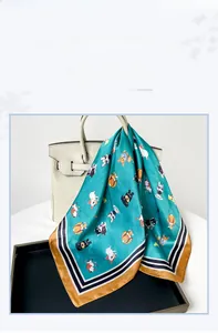 Französisches Satin-Halstuch mit Corgi-Mustern, drapiert über einer weißen Handtasche