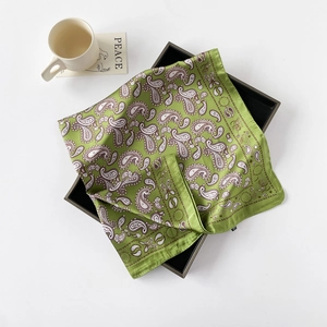 Detail eines grünen Seidenschals mit Paisley-Muster und glänzender Textur