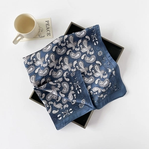 Detailansicht des dunkelblauen Seidenschals mit Paisley-Muster auf einem Tablett