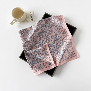 Detailansicht eines rosa Paisley-Seidentuchs auf einem Tablett mit Tasse und Karte