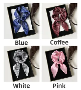 Détail de quatre foulards en satin paisley en bleu, café, blanc et rose dans des coffrets