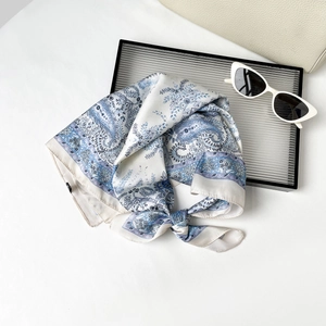 Détail d'un foulard en soie à motif paisley bleu avec lunettes de soleil et sac