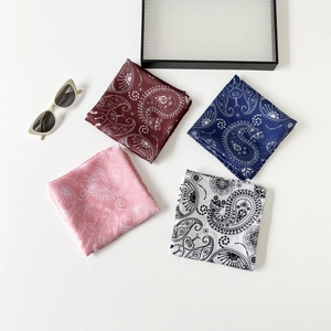 Detail view of four square paisley silk scarves in wine red, blue, and pink patterns