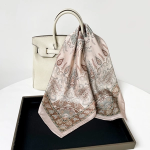 Détail d'un foulard en soie paisley rose drapé sur un sac à main en cuir aux motifs vintage