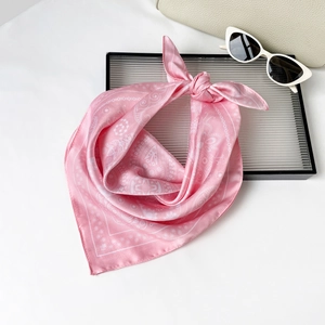 Close-up of pink paisley silk scarf paired with chic sunglasses and a beige handbag
