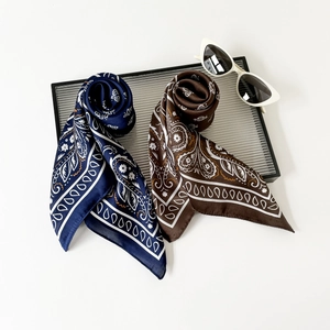 Detailed macro view of navy and brown paisley silk scarves with elegant satin texture