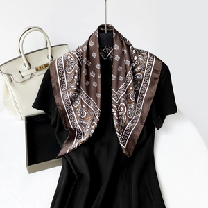 Detail of silk-feel scarf with white paisley pattern draped over a black dress