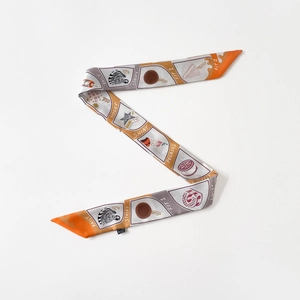 Détail d'un foulard twilly à motifs orange et gris avec imprimé zèbre et lettrage