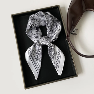 Macro detail of paisley print silk scarf with floral patterns on black and white satin fabric