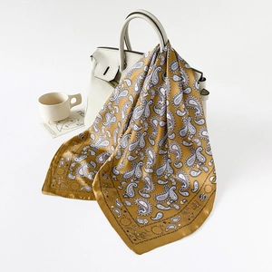 Nahaufnahme eines senfgelben Paisley-Seidentuchs, das elegant auf einer Tasche liegt