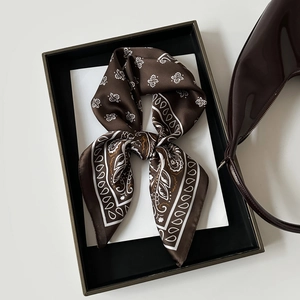 Detail of silk-like dark brown paisley square scarf with glossy shoulder bag in gift box