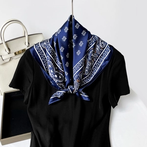 Detail of navy blue paisley silk scarf tied neatly on a black short sleeve top neck