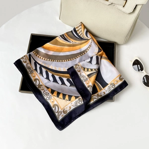 Dettaglio foulard in seta con stampa paisley accanto a borsa bianca e occhiali da sole