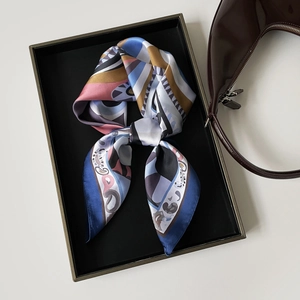 Dettaglio di un foulard in raso con motivi geometrici annodato con eleganza