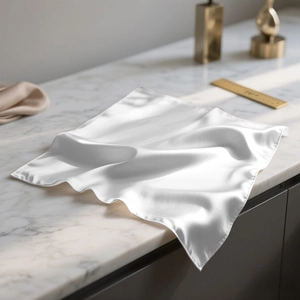 Détail d'un foulard en satin blanc sur marbre montrant la texture soyeuse