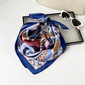 Dettaglio di un foulard in seta con stampe geometriche e accessori alla moda