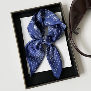 Detailed view of dark blue paisley silk scarf with white patterns tied on a brown handbag