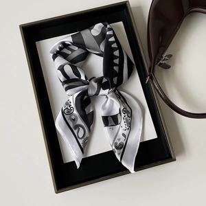 Dettaglio di un foulard in seta con stampa geometrica paisley in una scatola regalo