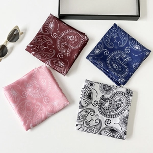 Four paisley printed silk scarves in red, navy, pink, and white with elegant sunglasses