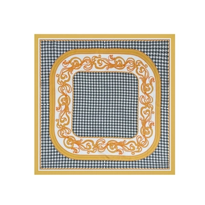 Close-up of elegant square silk scarf featuring black houndstooth and golden baroque patterns