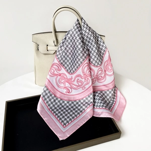 Detailed shot of houndstooth and baroque print silk scarf tied on a beige handbag handle