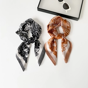 French forest print silk scarves in black and caramel colors on elegant white tray