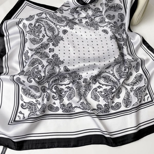 Dettaglio di foulard in seta paisley bianco e nero che mostra la trama in raso poliestere