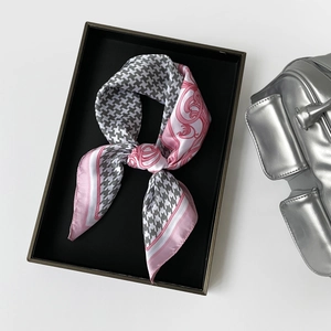 Detail of premium houndstooth and pink silk scarf tied in a bow inside a gift box