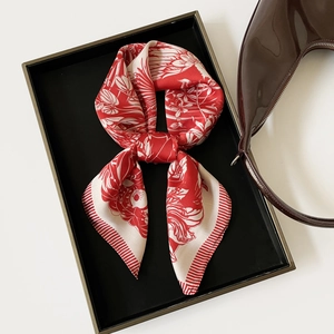 Detail of red and white silk scarf with floral print on display with a leather bag