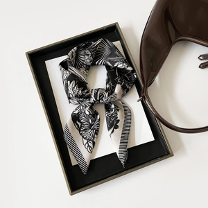 Detail view of a French style black and white floral silk scarf on a black tray