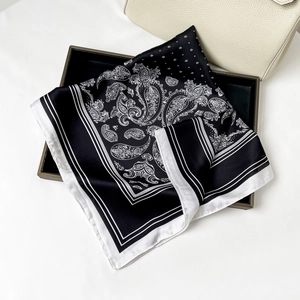 Dettaglio di un foulard in raso con motivo paisley bianco e nero su un vassoio