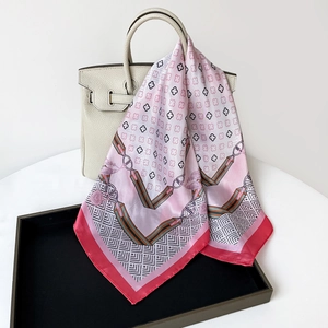 Close-up detail of clover printed pink satin scarf draped elegantly on a cream handbag