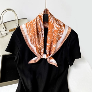 Detail of elegant orange floral silk scarf tied gracefully over a black t-shirt neckline