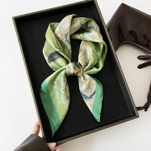 Detail of silk satin scarf with green oil painting print and dark green edges on a tray