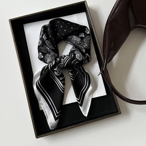 Dettaglio di un foulard in raso con motivo paisley in una confezione regalo