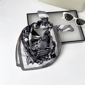 Detail view of a black and white French silk scarf with elegant botanical leaf prints
