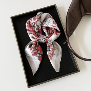 Detail of floral print satin scarf with smooth silk texture in a luxury display tray