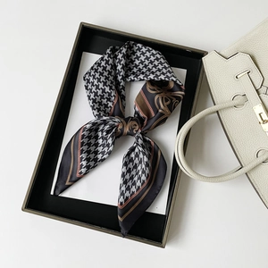 Close-up of houndstooth silk scarf in gift box with luxury leather handbag