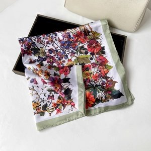 Detailed view of floral satin square scarf with green borders on a black display tray