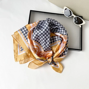 Elegant 70cm houndstooth and baroque silk scarf tied in a bow on a glass tray