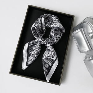 Detail of black and white paisley satin silk scarf on a premium display tray