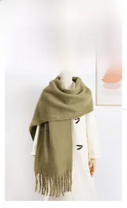 Detail of soft olive green mohair scarf with thick tassels and fuzzy texture on a coat