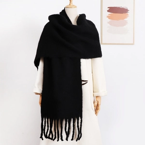 Elegant solid black mohair scarf with long tassels worn over a white coat for winter