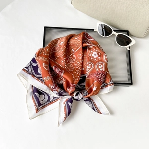 Close-up of luxury silk-like square scarf featuring retro paisley patterns and fine stitching