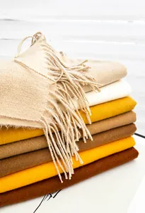 Close-up of stacked solid color pashmina scarves with soft texture and delicate tassels
