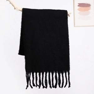 Close-up of thick black mohair knit scarf featuring long tassels and soft fluffy texture